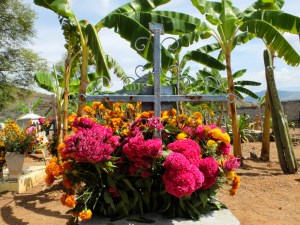 Red flowers and marigolds covering a grave site at San Pedro del Rincón cemetery.