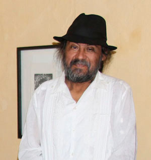 Portrait of Maestro Juan Alcázar. He is wearing a white guayabera and a dark hat.
